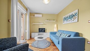 A modern living room with a blue sofa, patterned armchair, and a small coffee table. - Seafront Apt on Sunny Rab Island - Neda Maslina (Kampor)