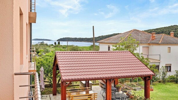 A covered outdoor seating area with a red roof, a wooden bench, and a table. - Seafront Apt on Sunny Rab Island - Neda Maslina (Kampor)