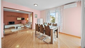 Un salon moderne avec un coin repas, un téléviseur et une cuisine en arrière-plan.