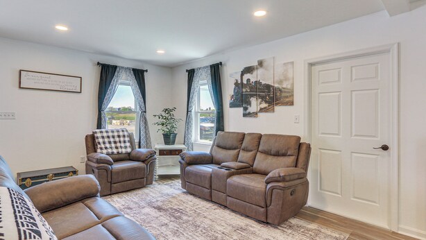 A living room with two reclining sofas, a coffee table, and a view of a cityscape through a window.