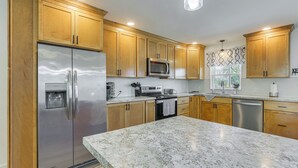 A modern kitchen with wooden cabinets, stainless steel appliances, and a marble countertop.