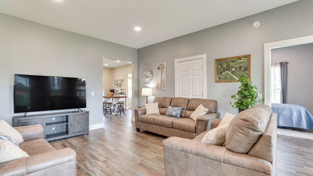 A spacious living room with a flat-screen TV, leather sofas, and a dining area with a table and chairs.