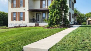 A two-story house with a front porch, a tree in front, and a sidewalk leading to the house.