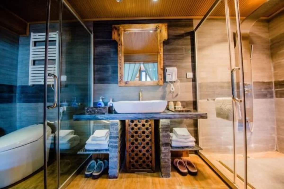 A modern bathroom with a glass shower enclosure, a wooden vanity, and a large mirror.