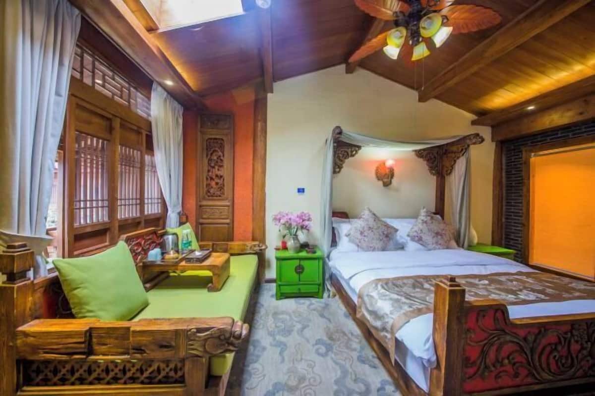 A traditional room with a bed, a green nightstand, a wooden sofa, and a decorative ceiling fan.