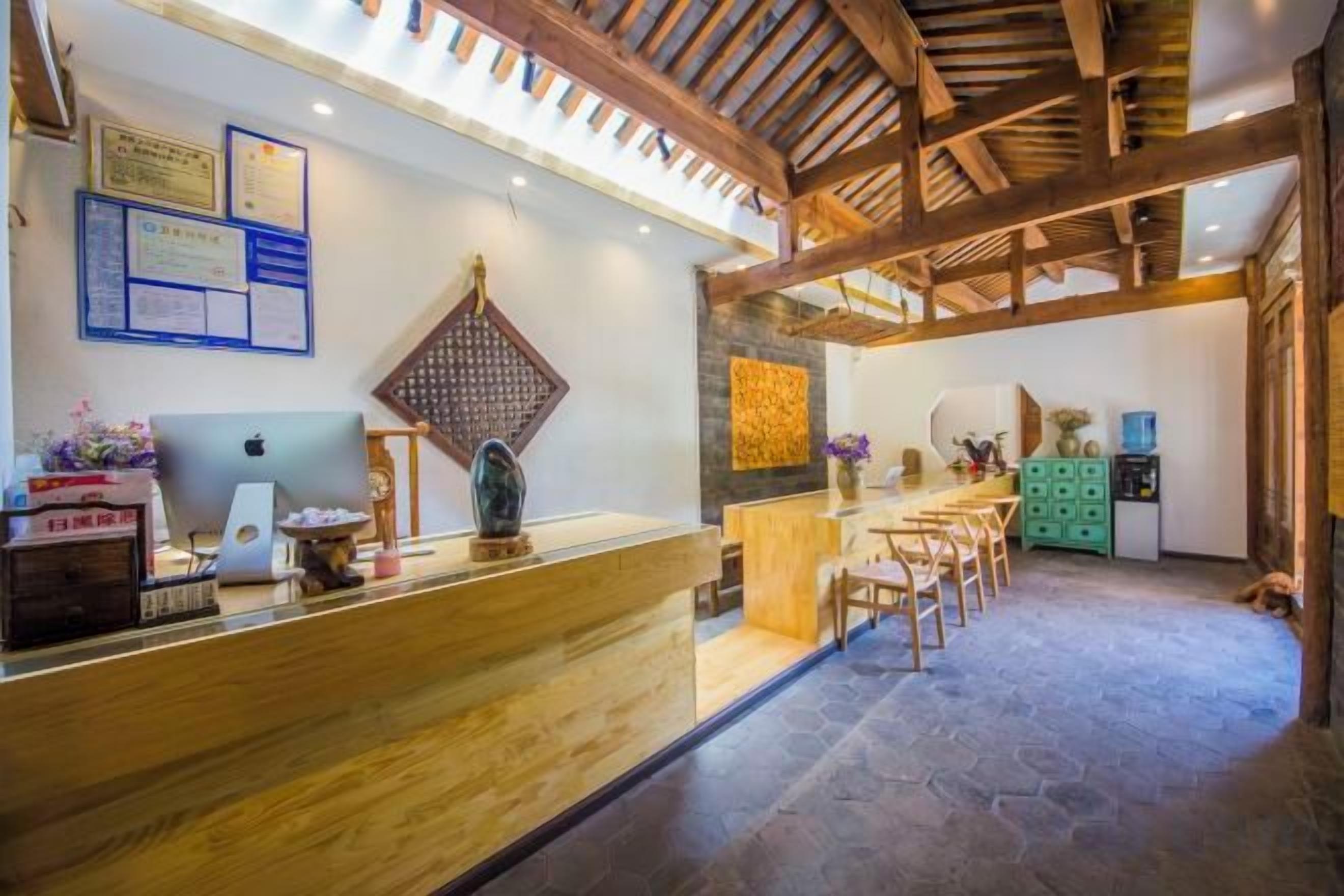 A reception area with a wooden reception desk, a seating area with chairs, and a stone floor.