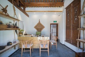 A traditional interior with a wooden ceiling, a central table with chairs, and a decorative wall piece. - Yun Qieman Inn· Panoramic Snow Mountain View & Golden Peak Sunrise (Old Town of Lijiang ) (Lijiang)