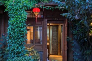 A traditional wooden building with a number '103' on the door, a red lantern, and a garden entrance. - Yun Qieman Inn· Panoramic Snow Mountain View & Golden Peak Sunrise (Old Town of Lijiang ) (Lijiang)