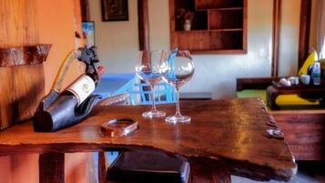 A wooden bar table with a bottle, glasses, and a small container.