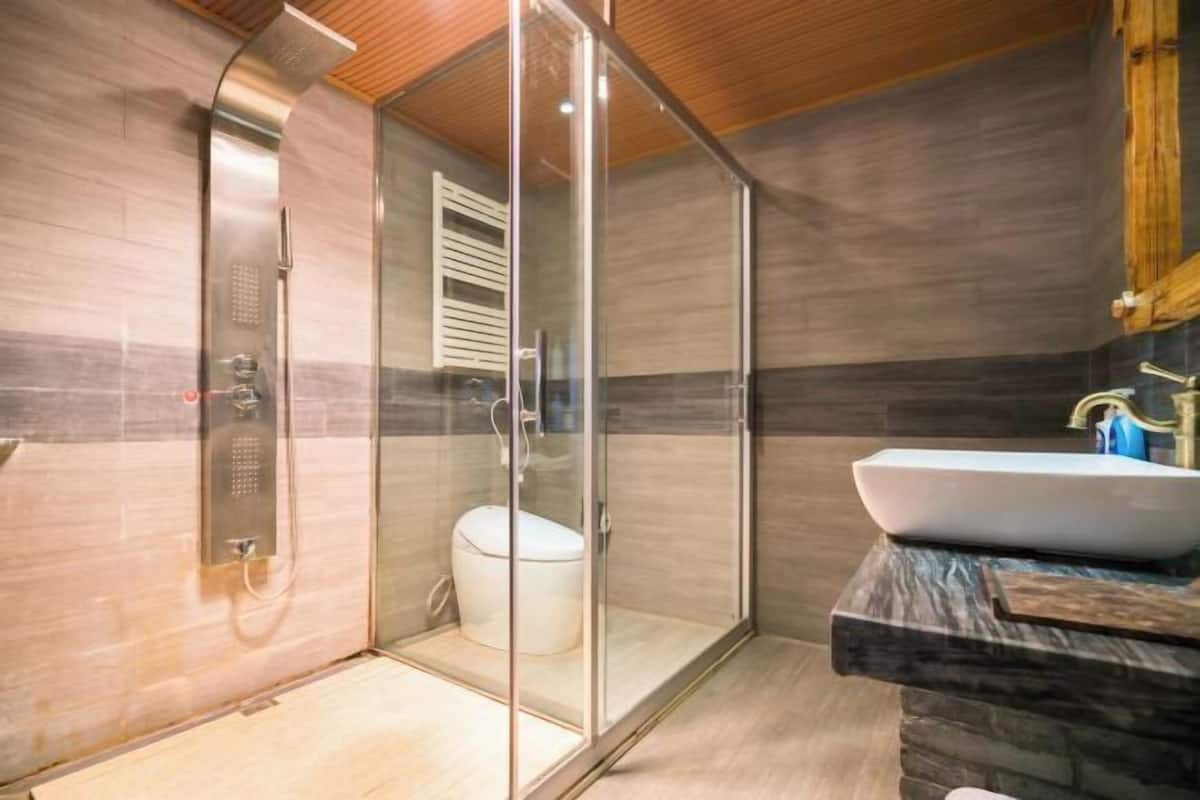 A modern bathroom with a glass-enclosed shower, a white toilet, and a marble countertop with a sink.