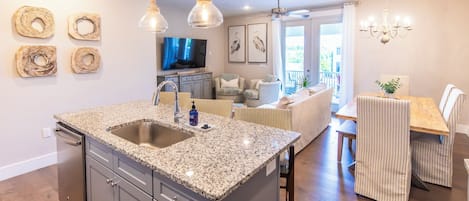 Una cocina moderna con encimeras de granito, un lavamanos integrado y un comedor con sillas a rayas y una mesa de madera.