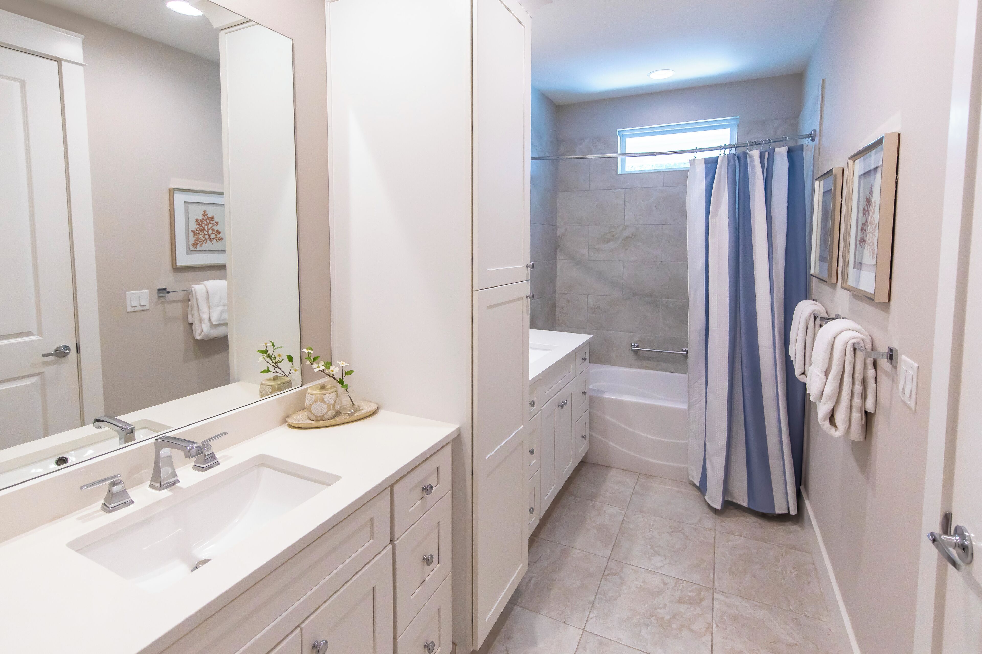 Un baño moderno con un espejo grande, dos lavamanos, una bañera y una cortina de ducha.