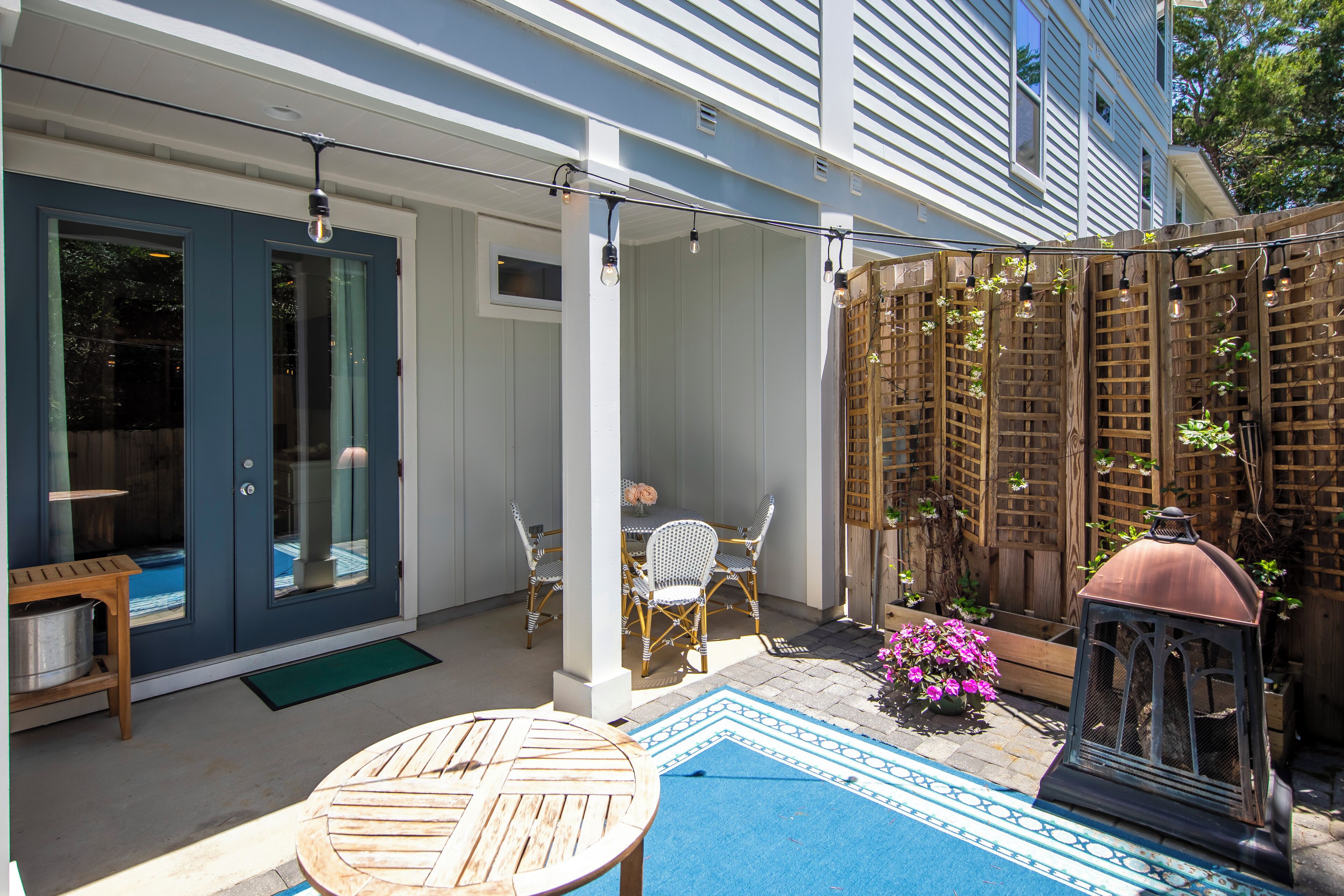 Une terrasse couverte avec une table et des chaises, une clôture en bois et une lanterne.