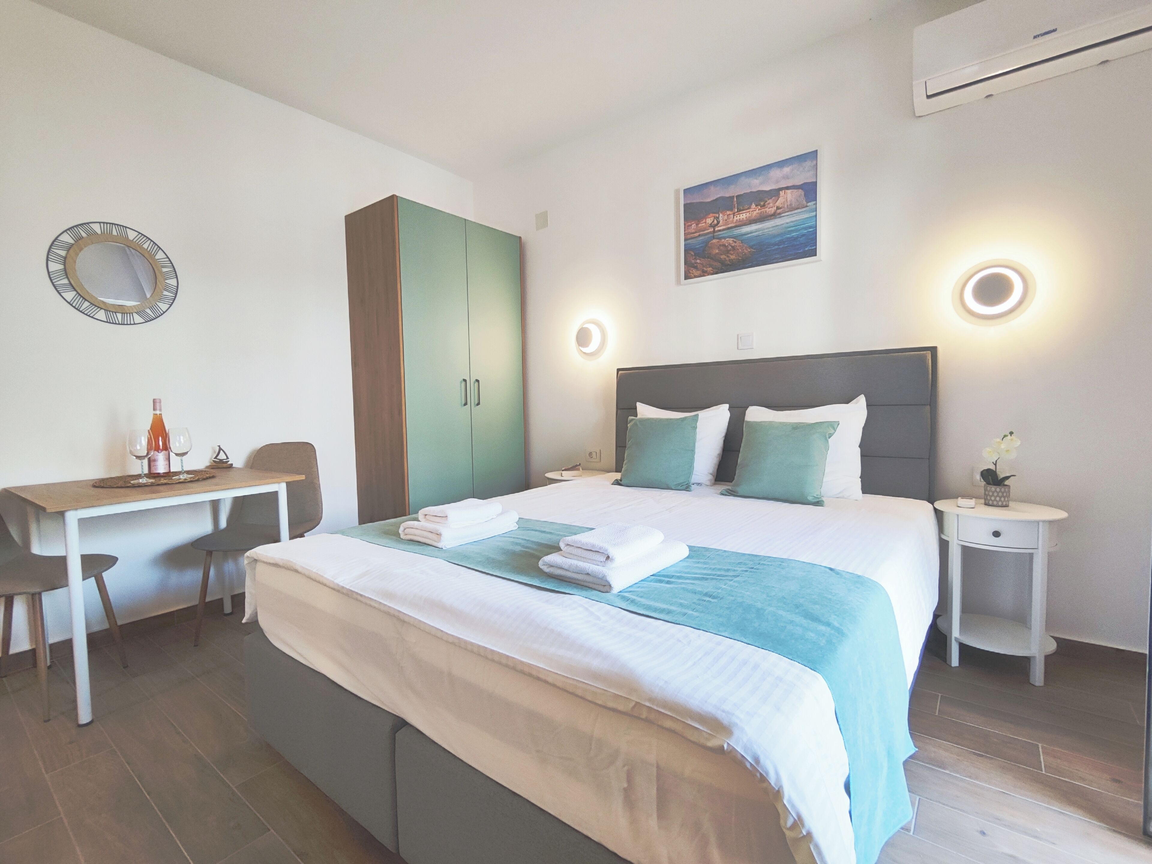 Una habitación de hotel moderna con una cama, un escritorio, una silla, un armario y un cuadro en la pared.