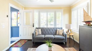 A living room with a grey sofa, a ceiling fan, and a door leading outside.