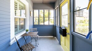 A narrow porch with a bench, a small table, and a potted plant.