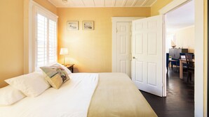 A hotel room with a bed, a ceiling fan, a desk, and a chair.