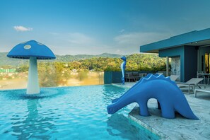 A swimming pool with a blue mushroom-shaped fountain and a blue dinosaur sculpture.