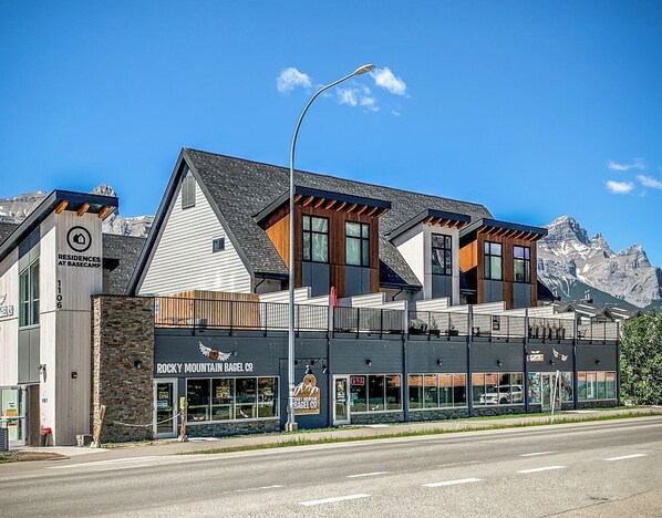 Un edificio moderno con el paisaje de las montañas como telón de fondo, con la leyenda 'Rocky Mountain Bagel Co.'