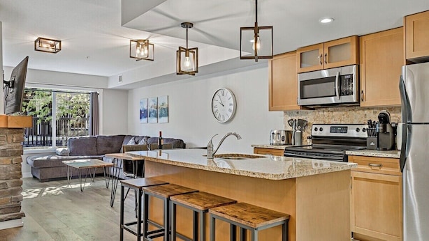 A modern kitchen with a central island, stainless steel appliances, and a stone backsplash.