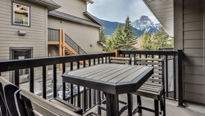 Un balcon avec une table et des chaises, donnant sur une chaîne de montagnes.