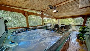 Un bain à remous avec une terrasse en bois, un barbecue et un espace extérieur aménagé avec des chaises et une table.