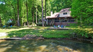 Une maison avec une terrasse, un petit quai et un ruisseau aux eaux claires qui la borde.