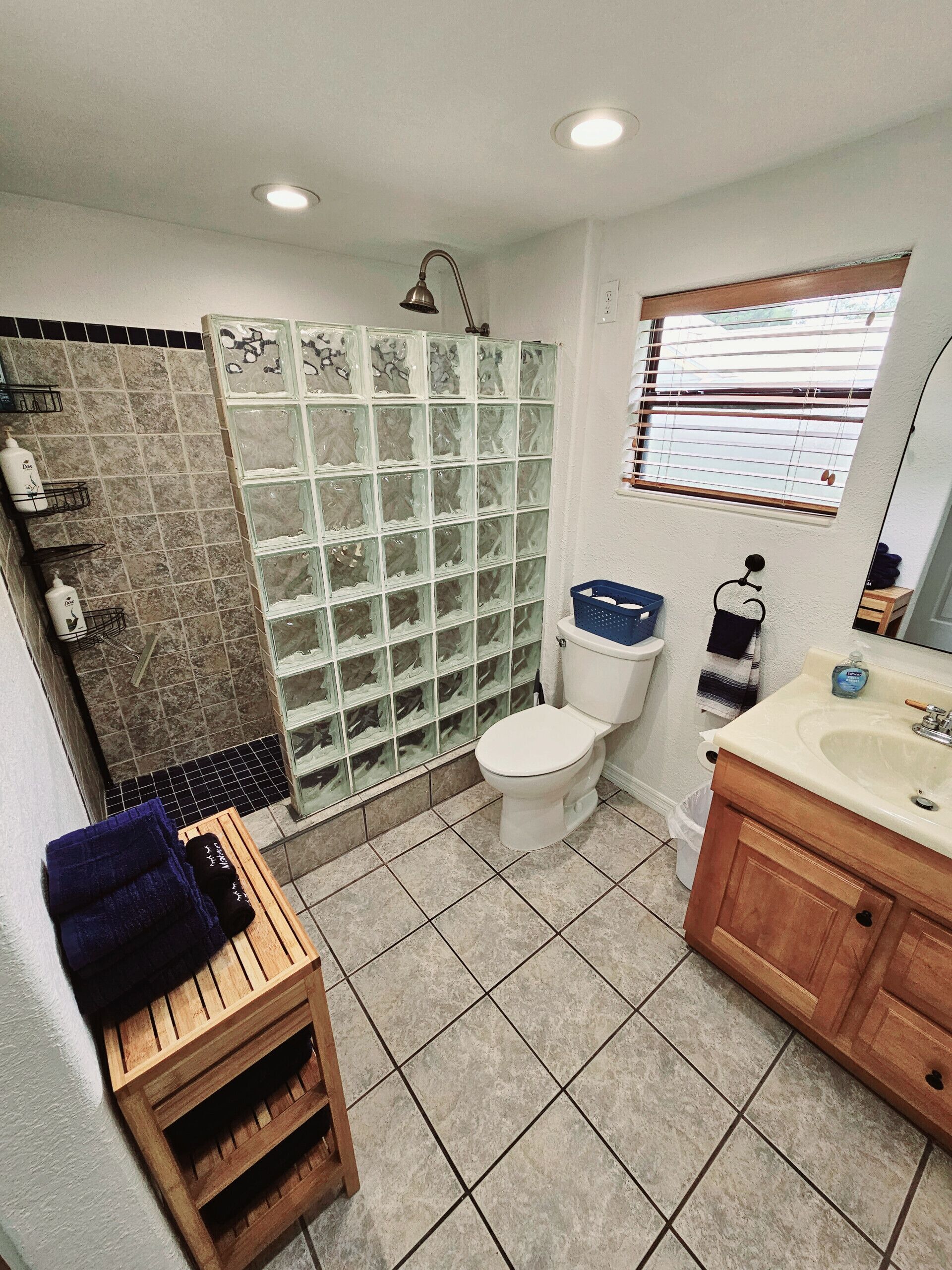 A bathroom with a shower, toilet, sink, and wooden vanity.