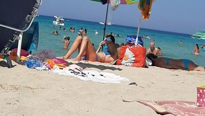 A beach with multiple colorful umbrellas and beach chairs, people sunbathing, and boats in the water. - Appartamenti Abate Perla del Golfo Home (Alcamo)