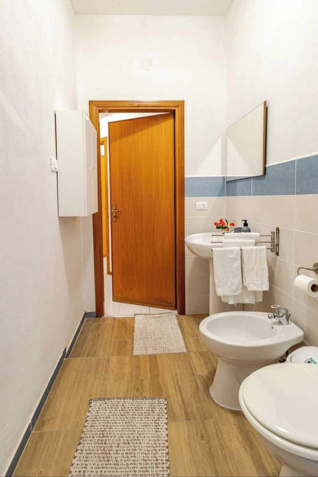 Et lille badeværelse med en trädør, en vask, en bidet og et toilet.