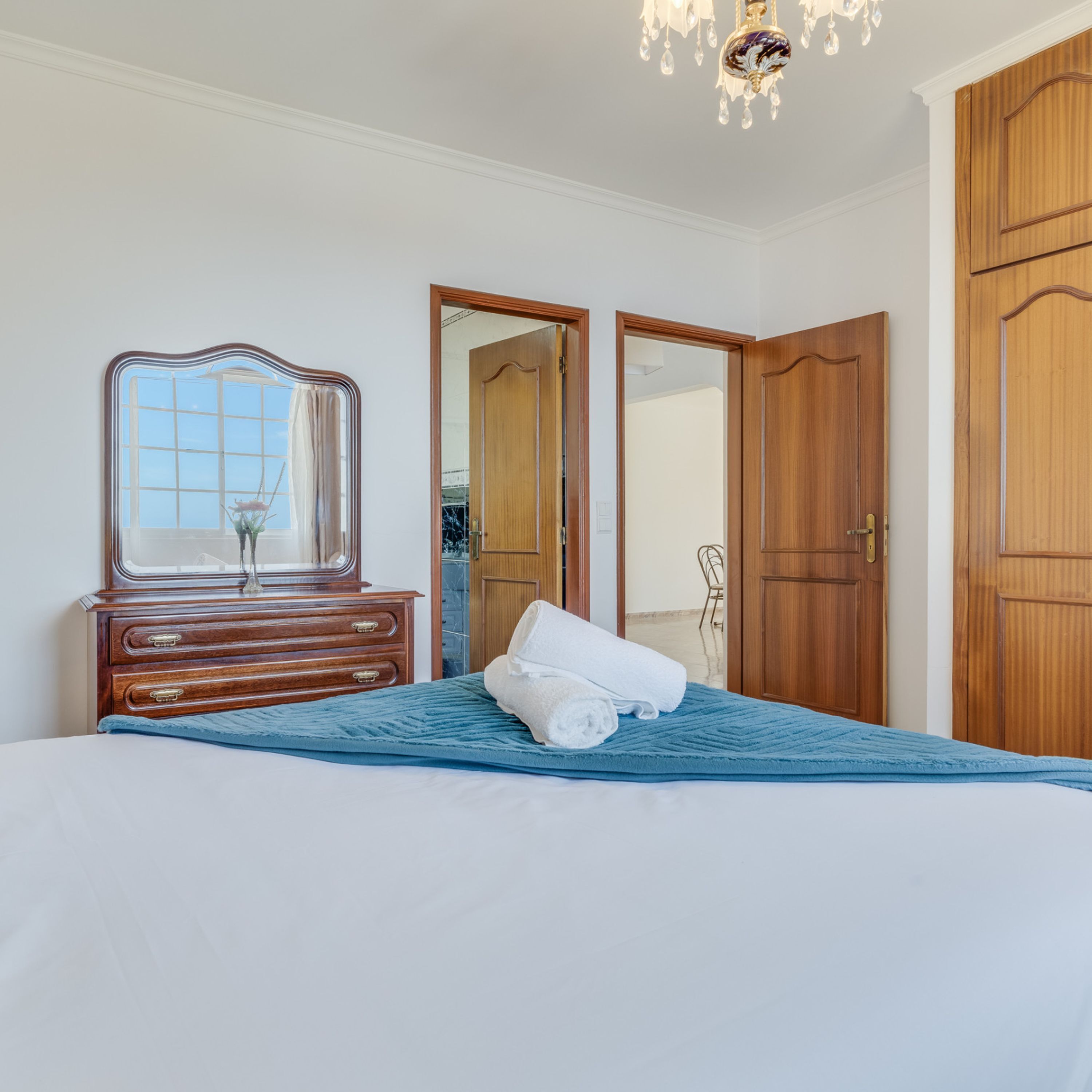A bedroom with a bed, a dresser, a mirror, and two doors.