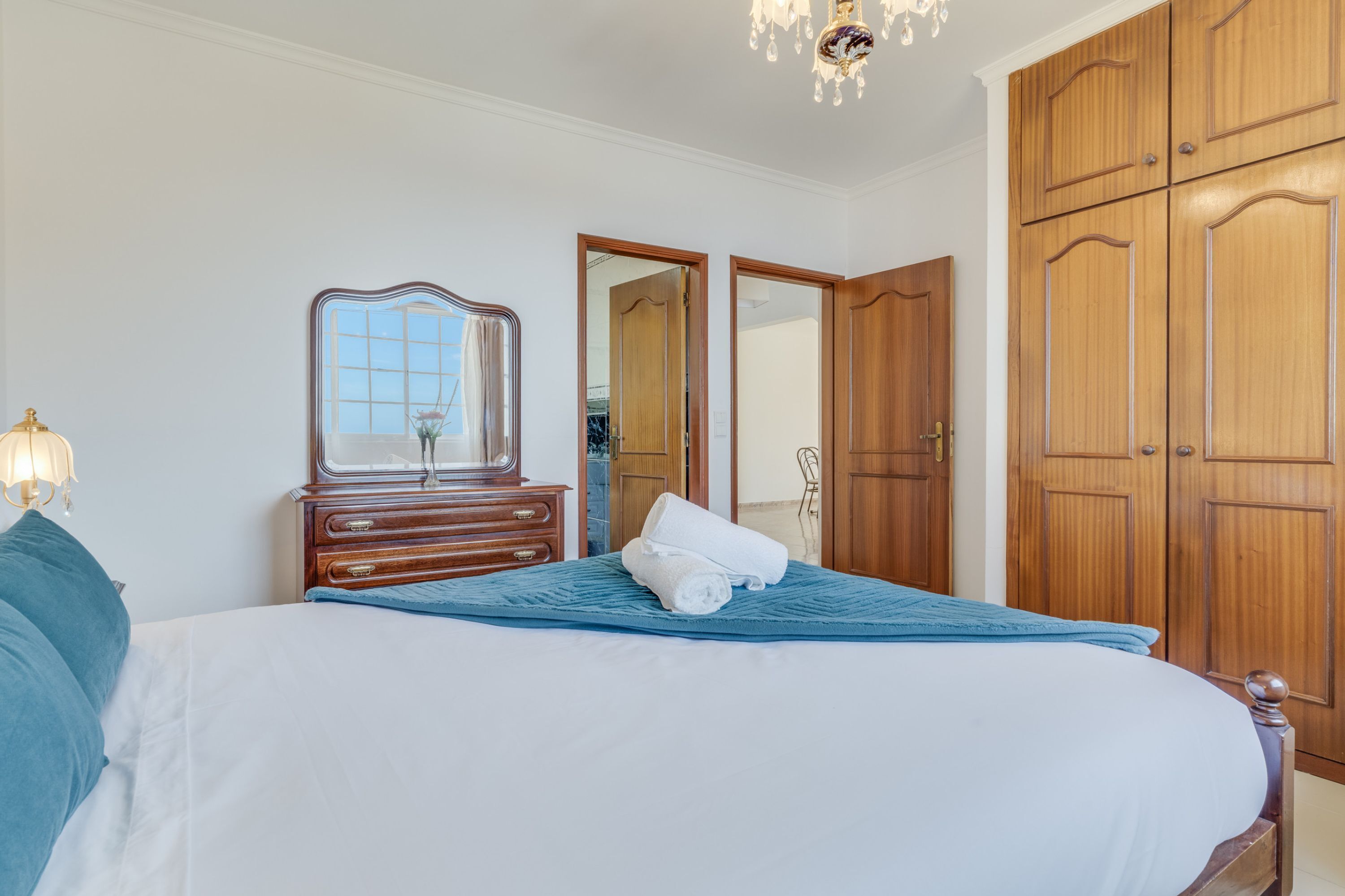 Ein Schlafzimmer mit Bett, Schminktisch, Spiegel und Holzschränken.