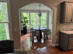 Una cocina con una mesa redonda, sillas grises y una planta en maceta.
