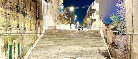 Vista nocturna de una calle con una empinada escalera que lleva a un edificio.