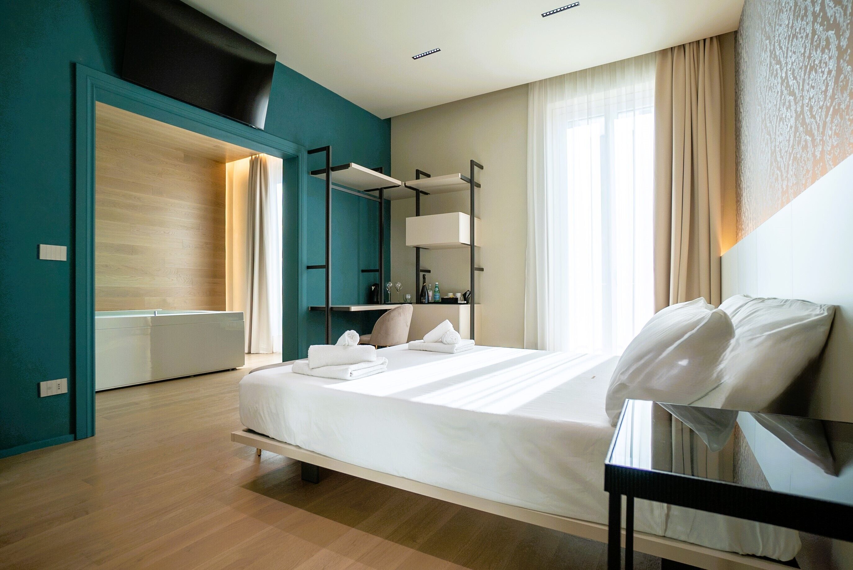 A modern hotel room with a bed, bedside table, and a built-in wardrobe.