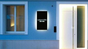 A hotel entrance with a sign reading "SAVANTO ROOMS" and a door with frosted glass panels.