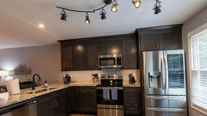 A modern kitchen with dark cabinets, stainless steel appliances, and a granite countertop. - Tre L at Watauga Lake - Butler, TN (Johnson County)