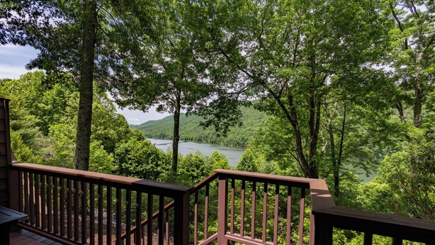 A wooden deck with a view of a lake surrounded by trees. - Tre L at Watauga Lake - Butler, TN (Johnson County)