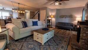 A living room with a sofa, coffee table, and a fireplace. There is a staircase leading to another level. - Tre L at Watauga Lake - Butler, TN (Johnson County)