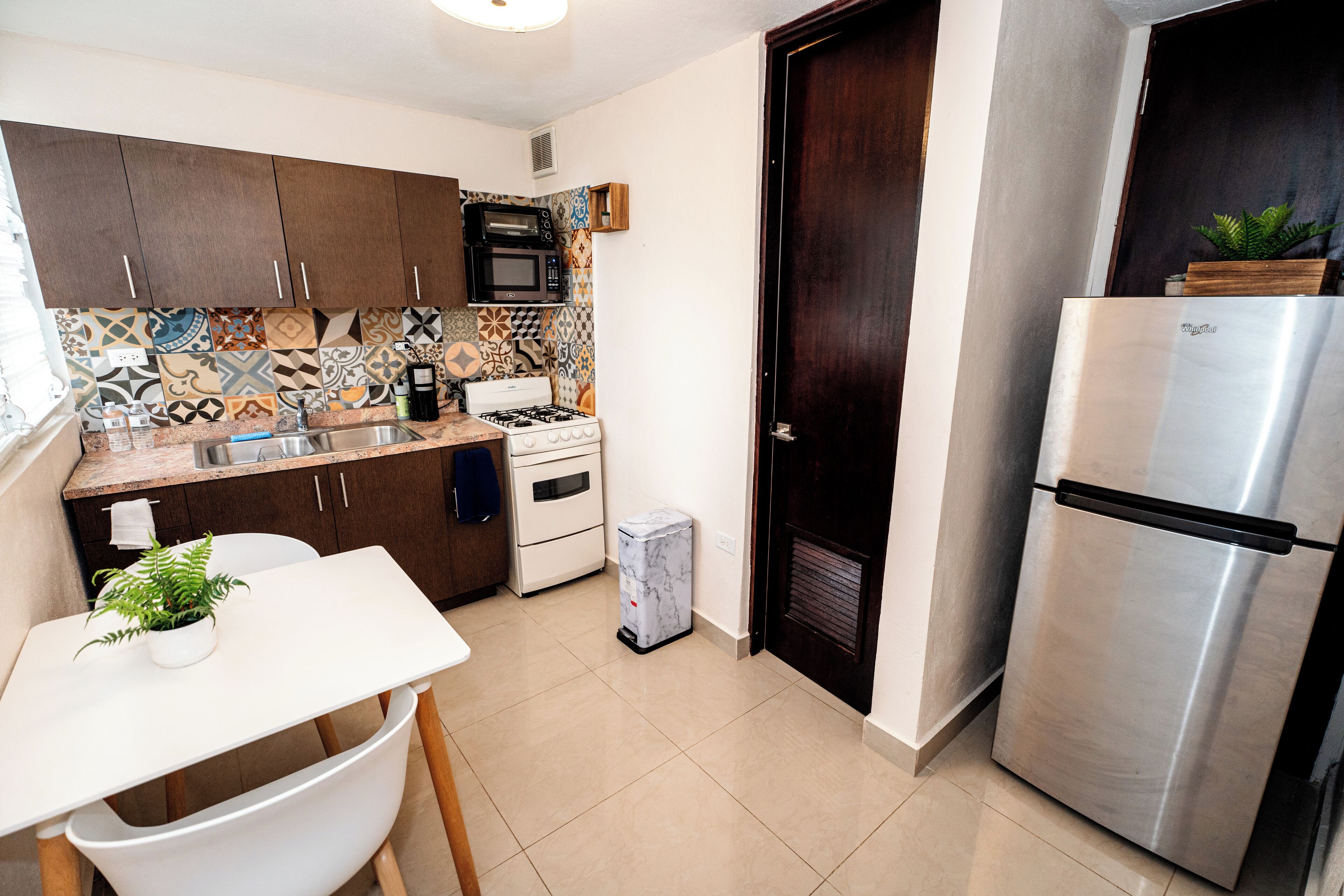 A compact kitchen with dark wooden cabinets, a stainless steel refrigerator, a microwave, and a gas stove.