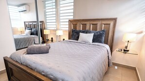 Ein Schlafzimmer mit einem großen Bett, einem Holzkopfstück, zwei Nachttischen mit Lampen und einem Spiegel an der Wand.