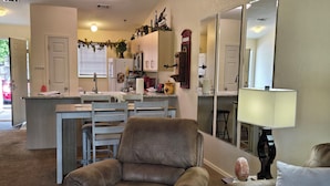 A living room with a brown leather armchair, a dining area with a kitchen in the background, and a large mirror on the wall. - ROMANTIC SUMMER GETAWAY FOR TWO!! EASY WALK-IN 1BD 1BA CONDO... NO STEPS!!! (Branson)