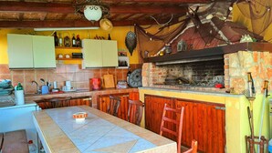 A rustic kitchen with a brick oven, wooden cabinets, and a tiled floor.