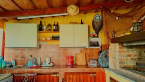 A rustic kitchen with wooden cabinets, a brick oven, and various kitchen utensils.