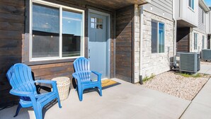 Un edificio con rivestimento in legno, una porta blu e due poltrone Adirondack blu all'esterno.