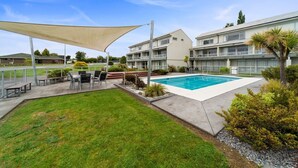 A hotel with a swimming pool, outdoor seating, and a covered patio area. - 300 Lake Terrace (Taupo)