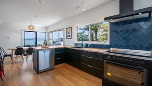 A modern kitchen with a built-in dishwasher, a stove, and a large window offering a view of the sea.