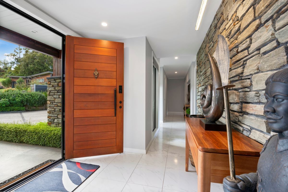 Une entrée moderne avec une porte en bois, un mur en pierre et une statue.