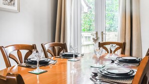 A dining area with a wooden table set for four, chairs, and a view of greenery outside through a glass door. - 2 bedroom accommodation in Longridge (Longridge)