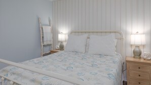 Ein Schlafzimmer mit einem Bett, Nachttischlampen, einem Nachttisch und einer Kommode.